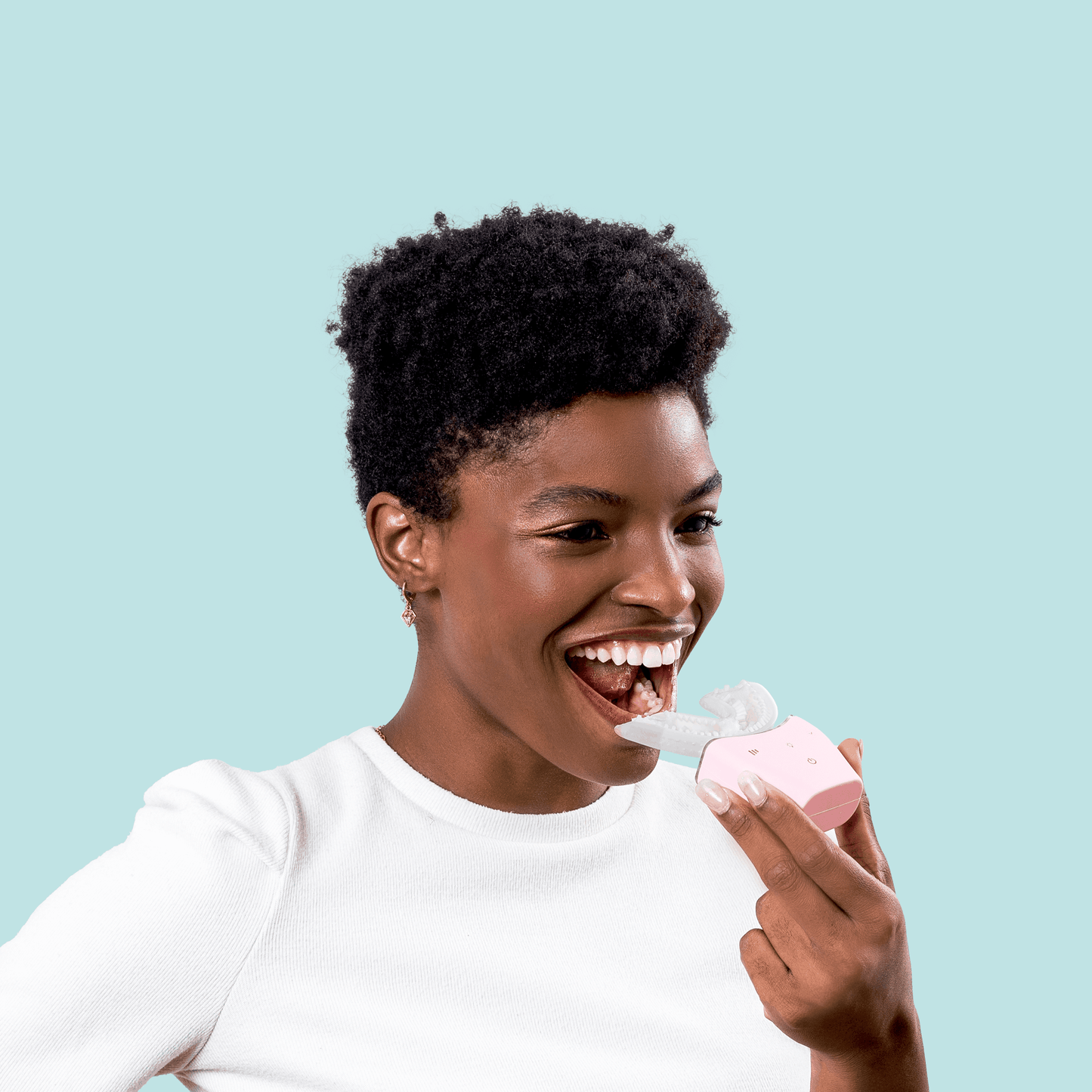 Woman using a pink Autobrush Sonic Pro U-shaped electric toothbrush with silicone bristles for hands-free, fast teeth cleaning.